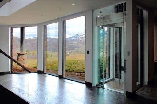 glass elevator next to a set of windows with scenic view.
